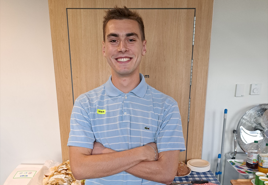 FNSC volunteer Frank stands smiling at the camera, with his arms crossed, wearing a blue striped tshirt.