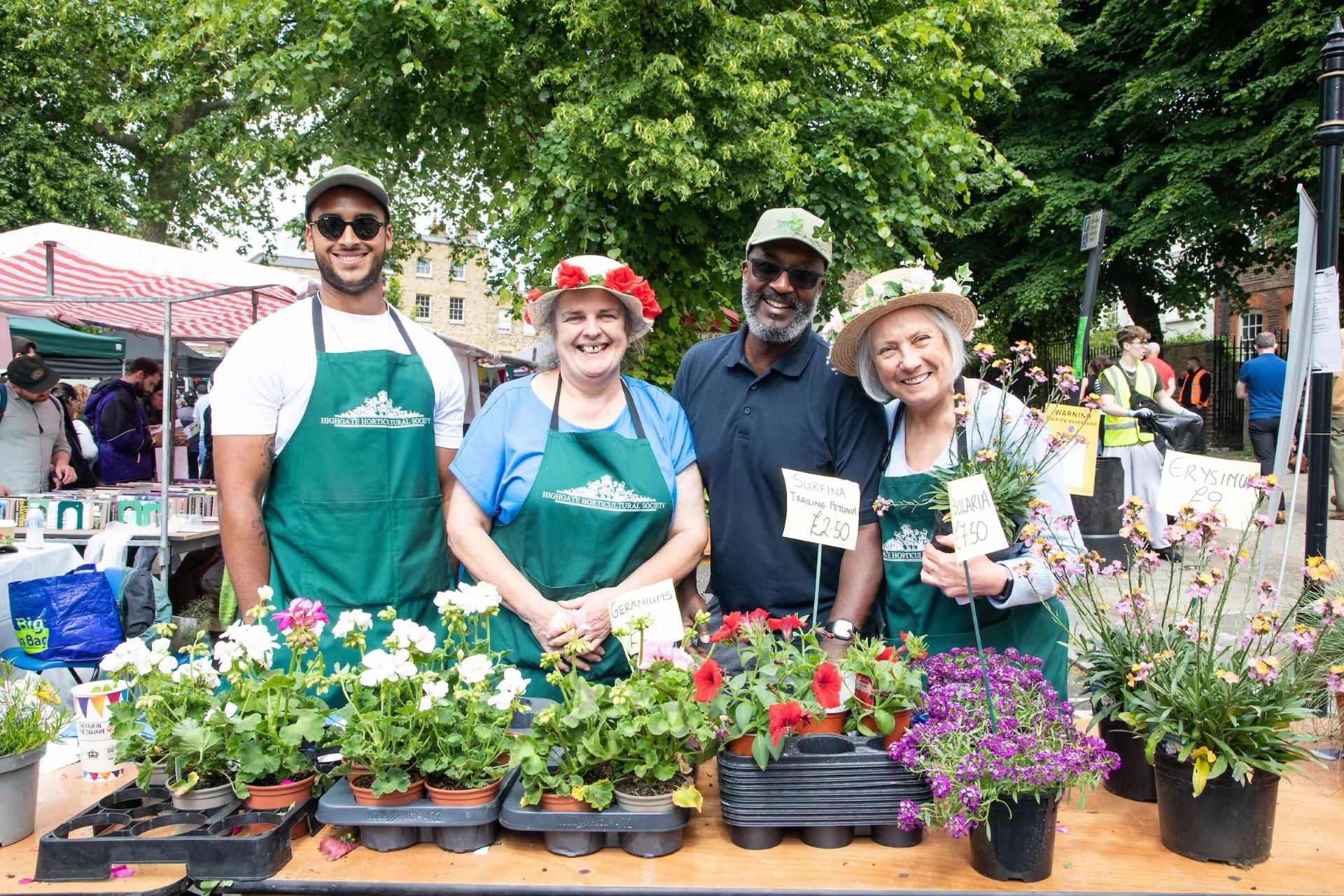 People standing by some plants that they are selling